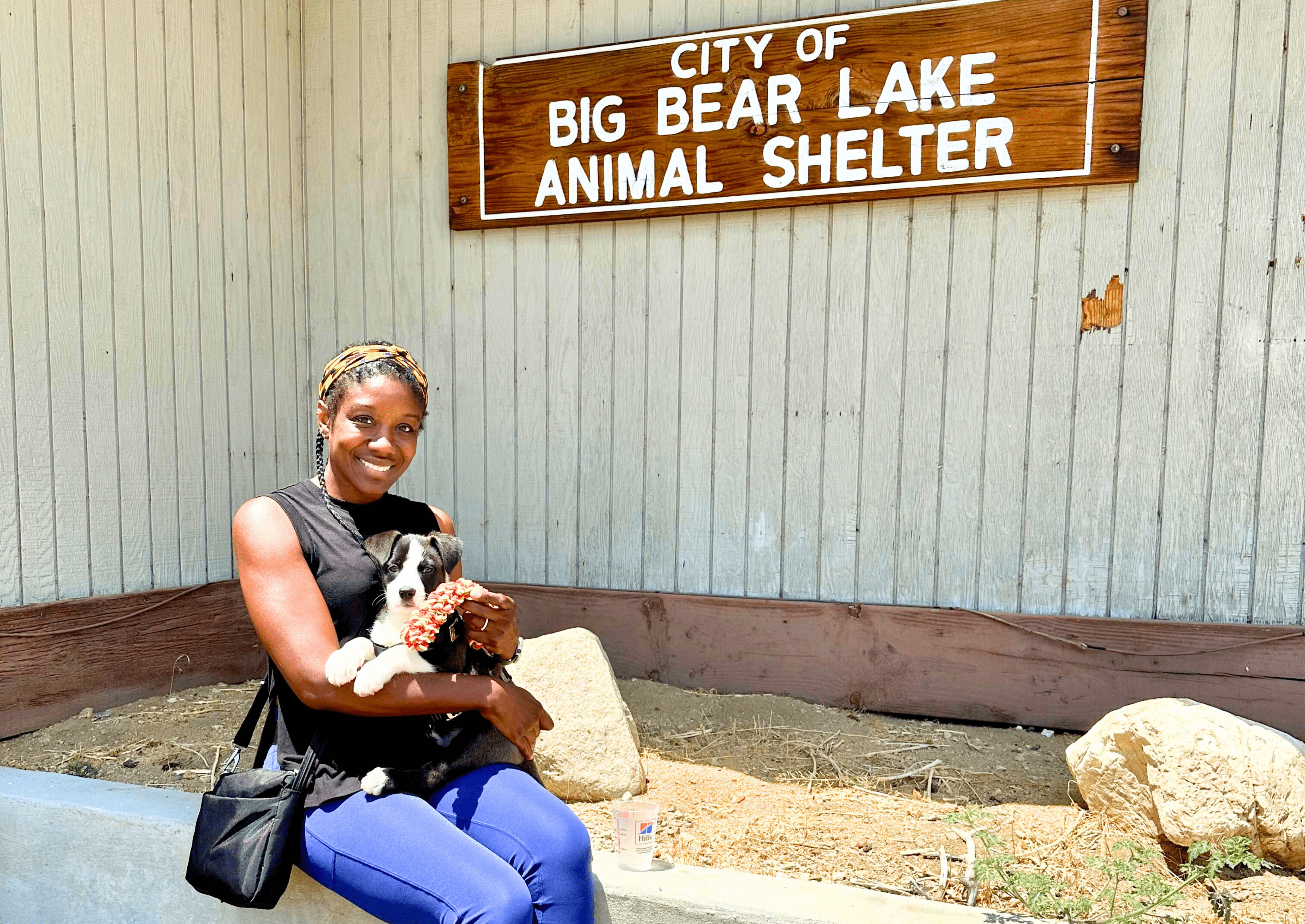 A lady smiling with the puppy she adopted outside of Big Bear Animal Shelter