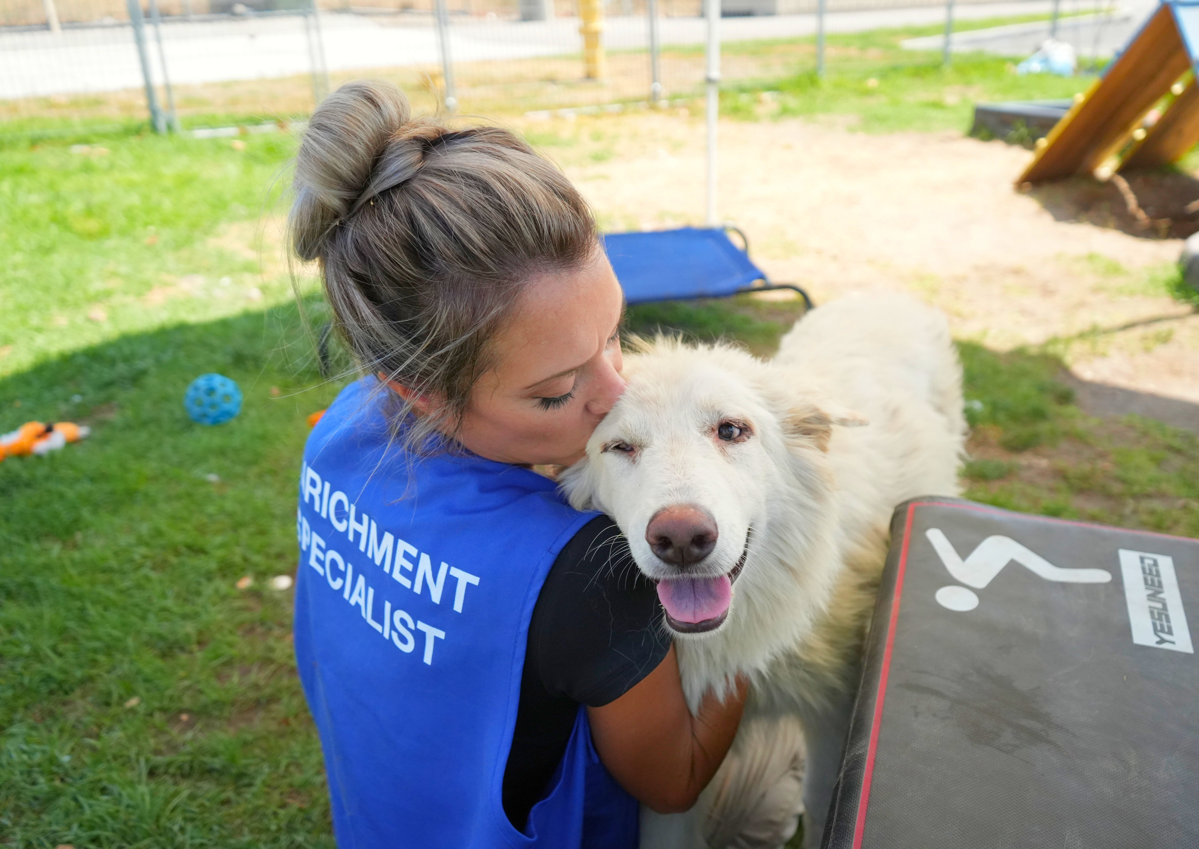 Enrichment Specialist giving a kiss to a pet while petting the dog